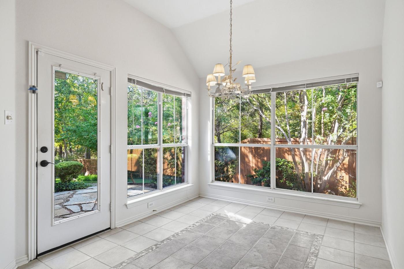 Breakfast nook with vaulted ceiling, windows on two sides, and door to the patio