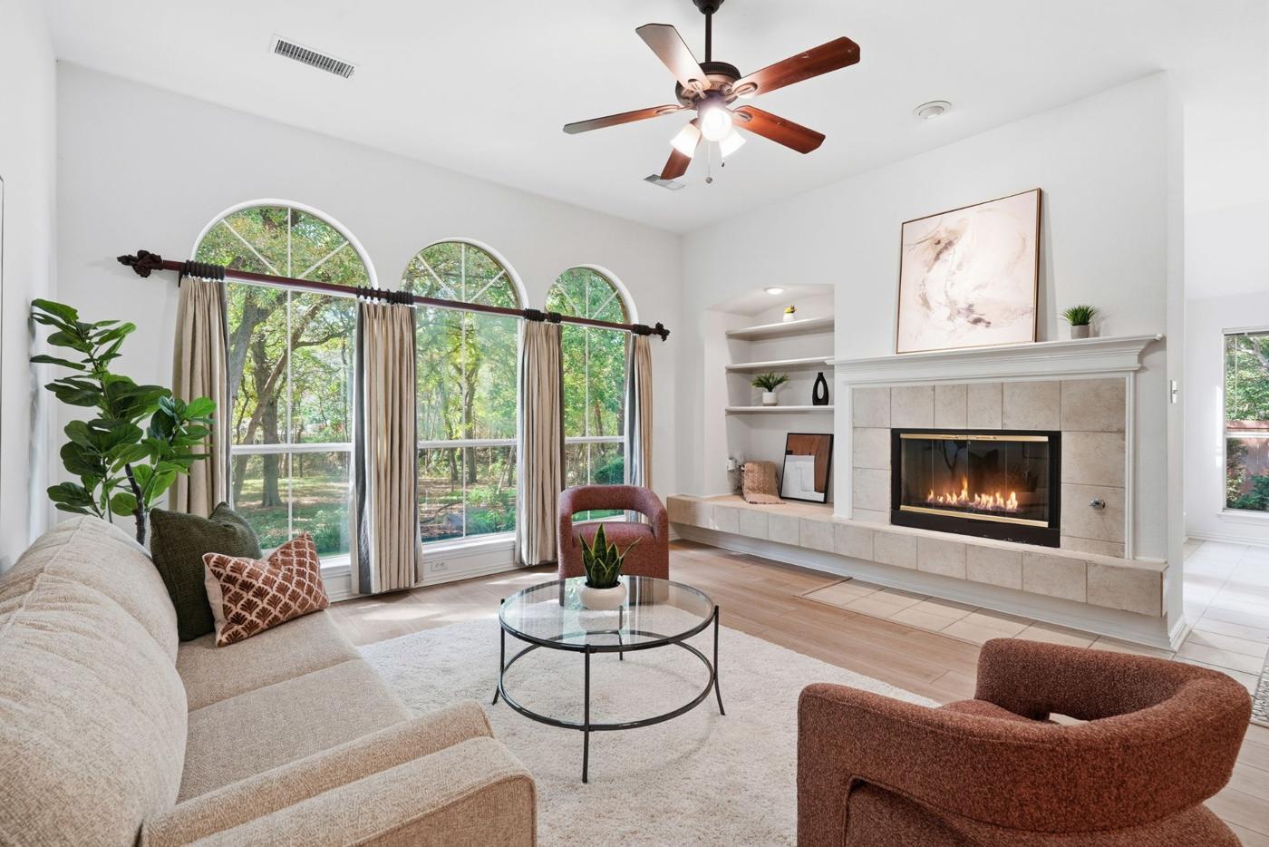 Family room with three arched windows and a tiled fireplace with built-in shelves