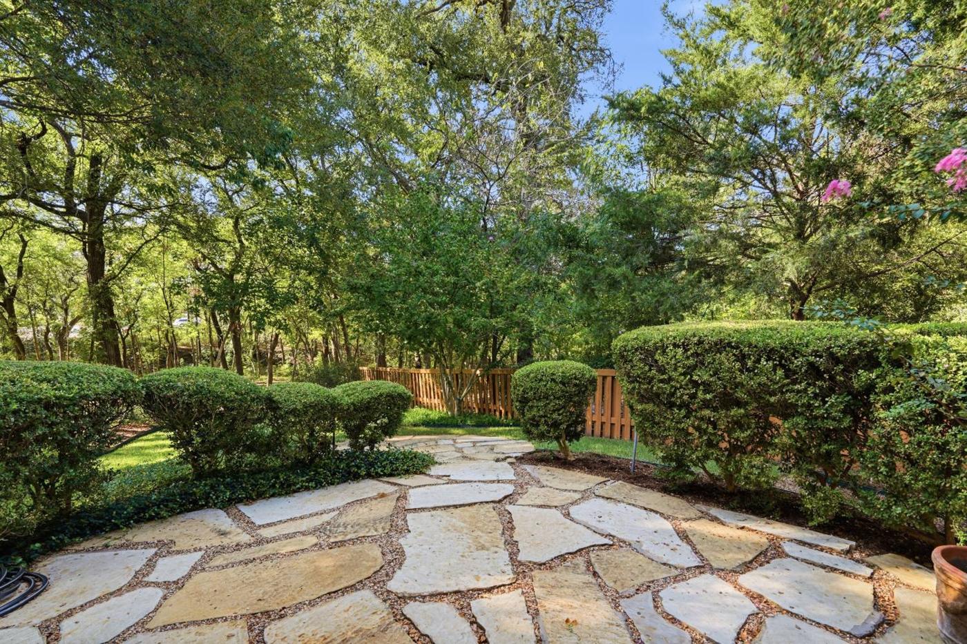 Flagstone patio surrounded by trees and shrubs