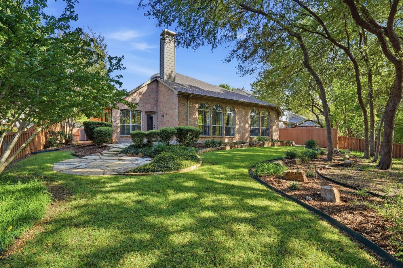 Back of the brick home with a flagstone path through the lawn