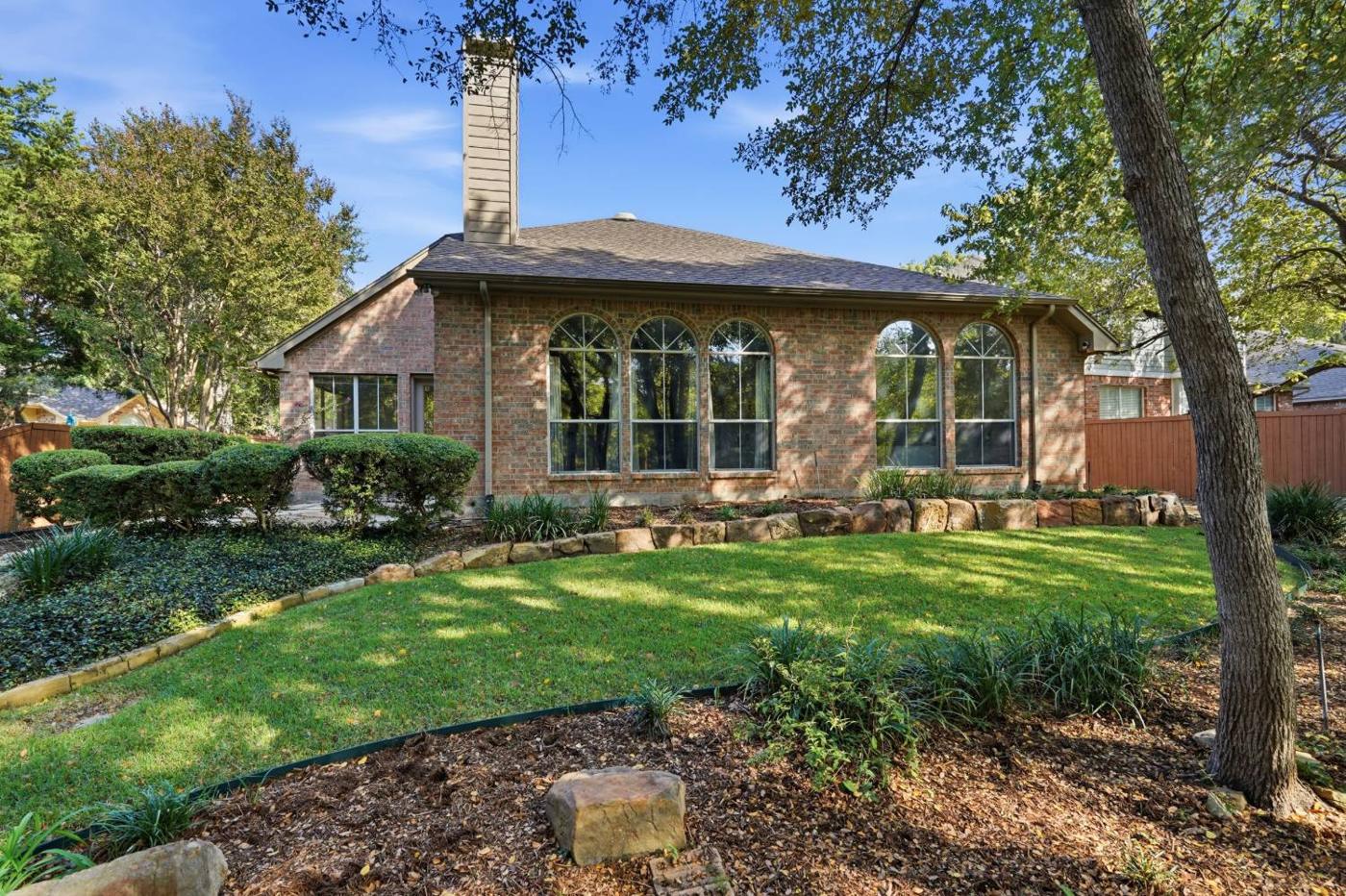 Back of the home with arched windows facing the trees